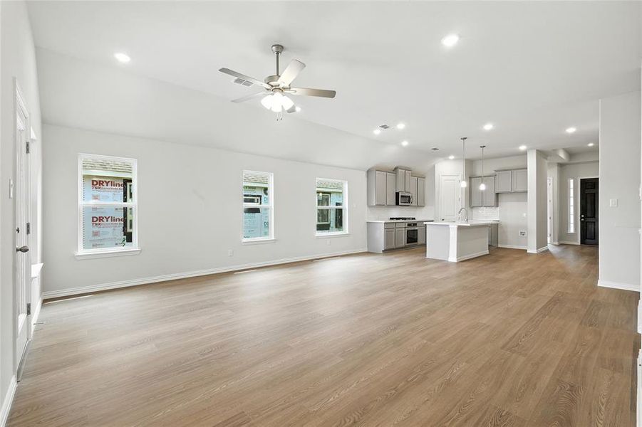 Unfurnished living room featuring recessed lighting, light wood finished floors, ceiling fan, and lofted ceiling Unfurnished living room featuring recessed lighting, light wood finished floors, ceiling fan, and lofted ceiling