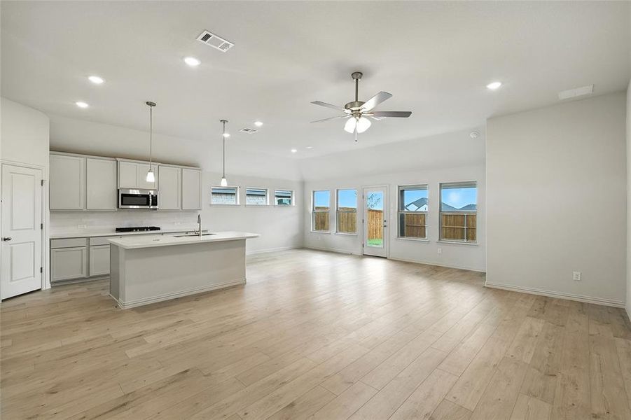 Kitchen featuring an island with sink, decorative light fixtures, recessed lighting, open floor plan, and light wood-style flooring Kitchen featuring an island with sink, decorative light fixtures, recessed lighting, open floor plan, and light wood-style flooring