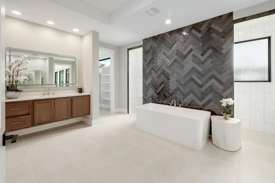 Luxurious bathing area features a deep soaking tub against a dramatic tile accent wall.