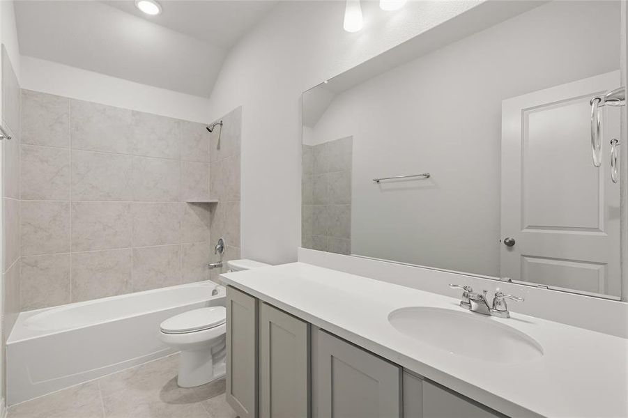 Full bathroom with shower / bath combination, vanity, vaulted ceiling, and light tile patterned floors Full bathroom with shower / bath combination, vanity, vaulted ceiling, and light tile patterned floors