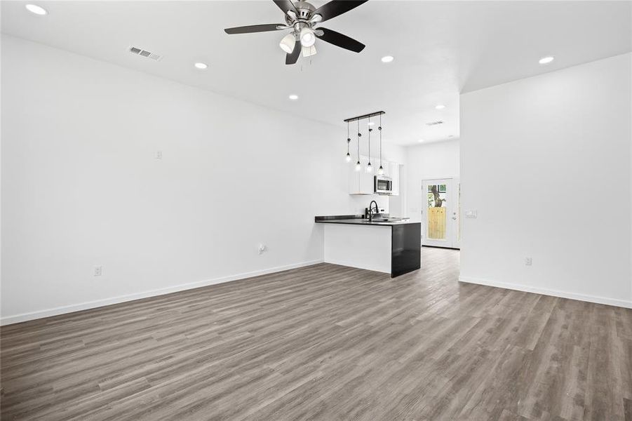 Unfurnished living room featuring ceiling fan, sink, and dark hardwood / wood-style floors