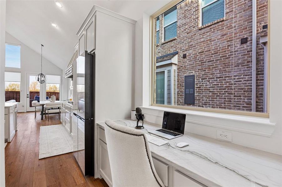 Home office with high vaulted ceiling, brick wall, and dark wood-type flooring