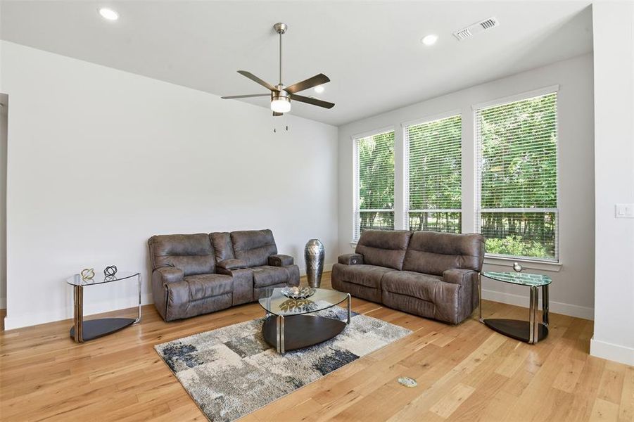 Spacious living area featuring light wood-finish flooring, recessed lighting, and a ceiling fan Spacious living area featuring light wood-finish flooring, recessed lighting, and a ceiling fan
