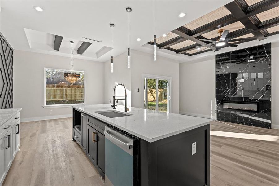 Kitchen featuring light stone countertops, stainless steel dishwasher, a kitchen island with sink, sink, and light hardwood / wood-style flooring