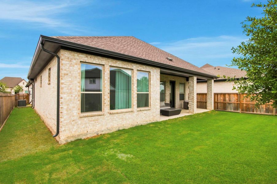 Spacious backyard with a covered patio, offering a comfortable setting for outdoor entertaining, relaxation, and everyday enjoyment.