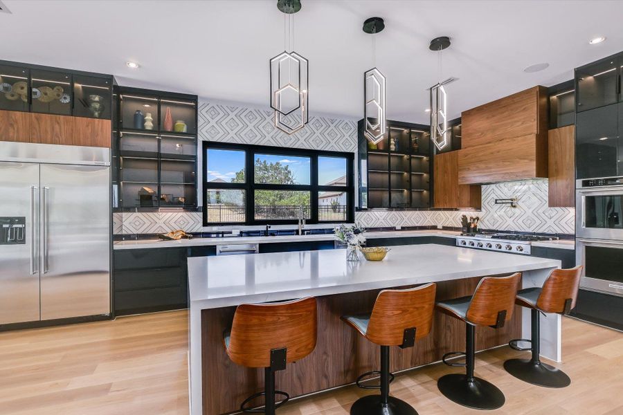 Kitchen featuring stainless steel appliances, backsplash, glass insert cabinets, light quartz countertops, and light wood finished floors Kitchen featuring stainless steel appliances, backsplash, glass insert cabinets, light quartz countertops, and light wood finished floors