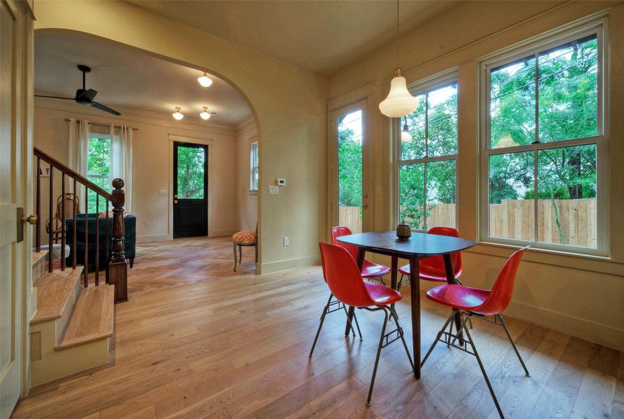 hardwood floors extend throughout this open living and dining area, naturally illuminated by numerous windows.