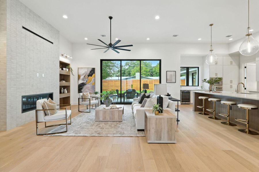 Living room featuring a tile fireplace, recessed lighting, light wood-style floors, wine cooler, and a ceiling fan Living room featuring a tile fireplace, recessed lighting, light wood-style floors, wine cooler, and a ceiling fan