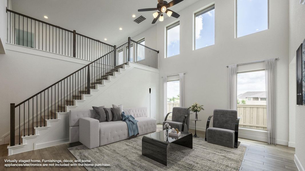 Living room with a towering ceiling, ceiling fan, stairway, wood finished floors, and recessed lighting Living room with a towering ceiling, ceiling fan, stairway, wood finished floors, and recessed lighting