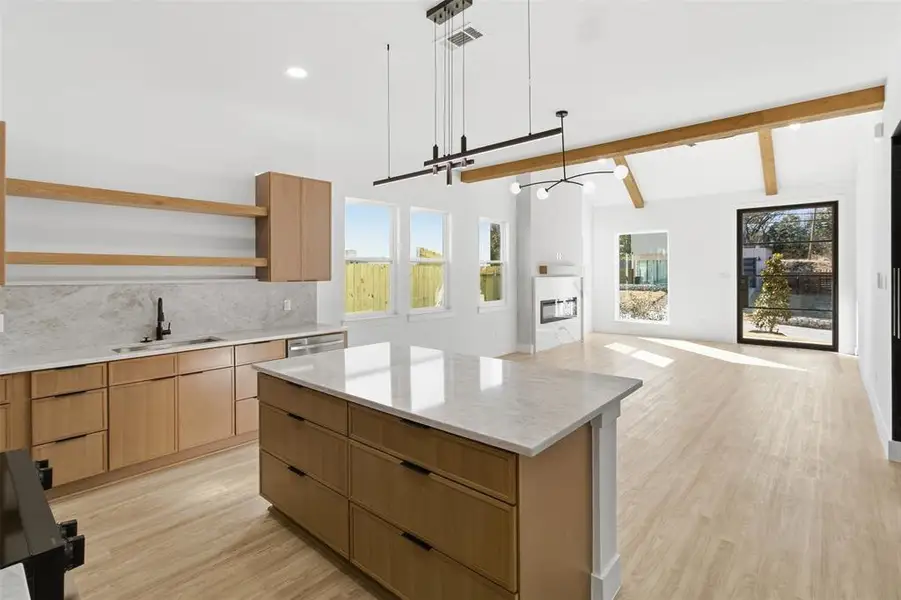 Kitchen with light stone countertops, pendant lighting, light wood-type flooring, a center island, and modern cabinets