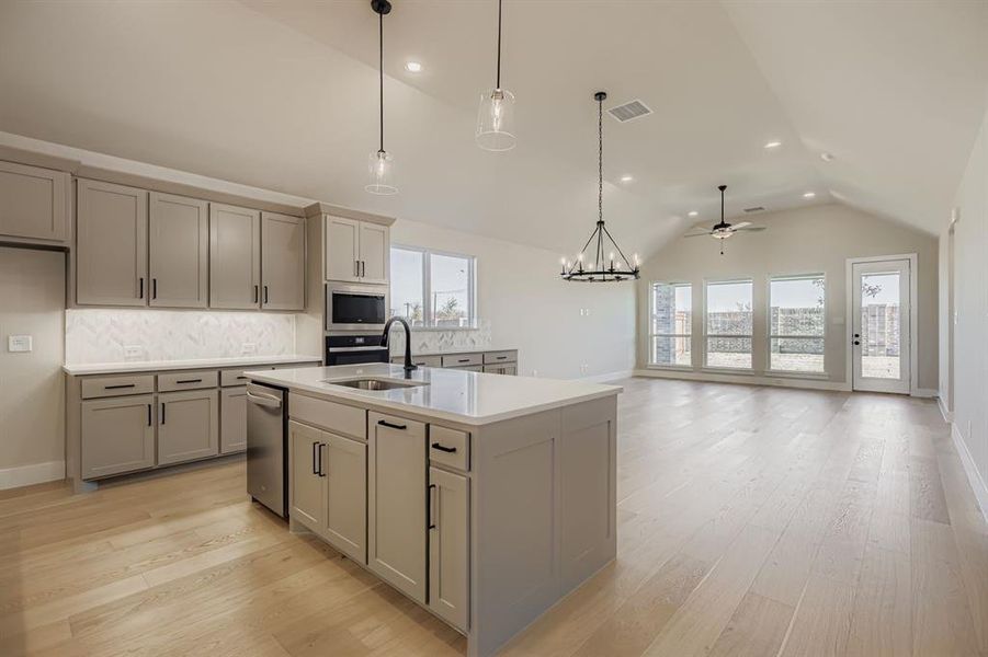 Kitchen featuring a chandelier, decorative light fixtures, a kitchen island with sink, light wood finished floors, and recessed lighting