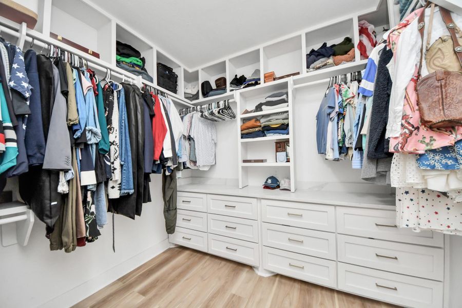 Spacious walk-in closet with ample hanging space, built-in shelves and drawers. Spacious walk-in closet with ample hanging space, built-in shelves and drawers.