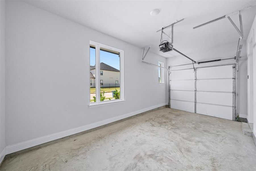 Garage with baseboards and a garage door opener