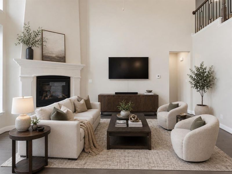 Living area featuring a fireplace with a white mantel, high ceilings, dark wood-finish flooring, and an open upper-level railing Living area featuring a fireplace with a white mantel, high ceilings, dark wood-finish flooring, and an open upper-level railing