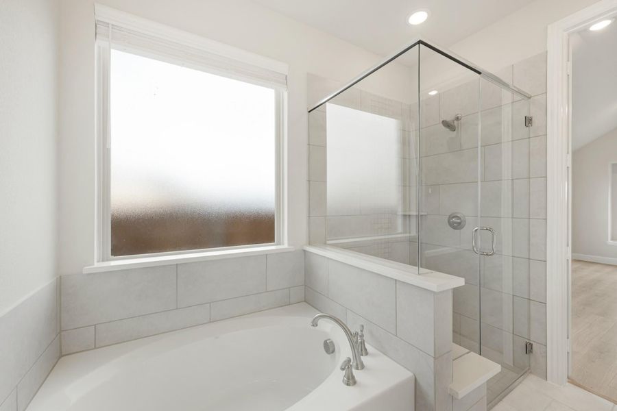 Bathroom with soaking tub, glass-enclosed tile shower, and frosted privacy window