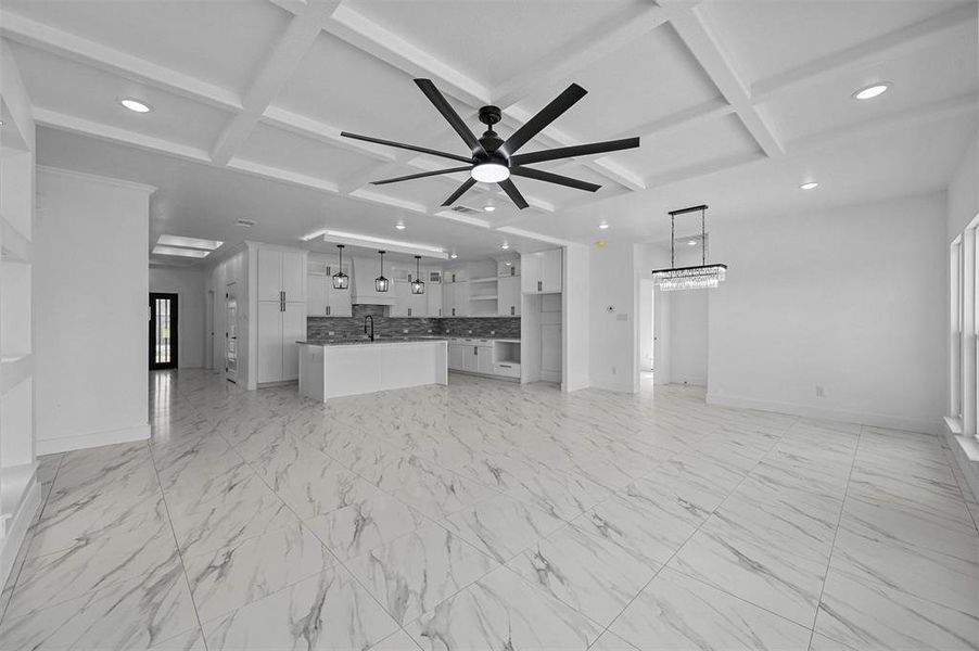 Unfurnished living room with beam ceiling, light tile patterned flooring, coffered ceiling, and ceiling fan