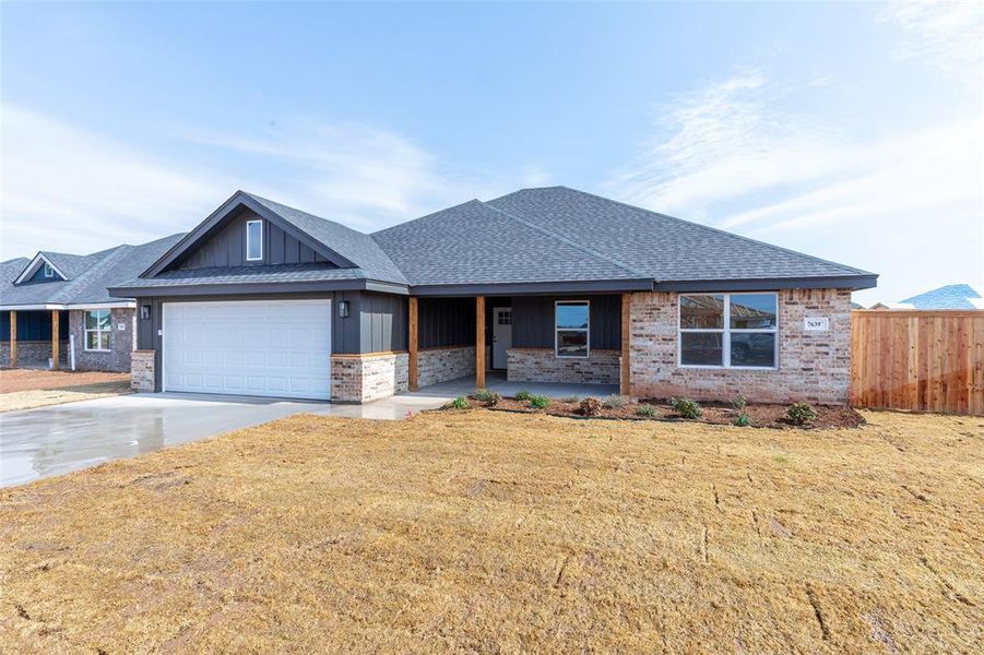 Contemporary ranch-style home featuring a dark gray vertical siding and light-toned brick facade
