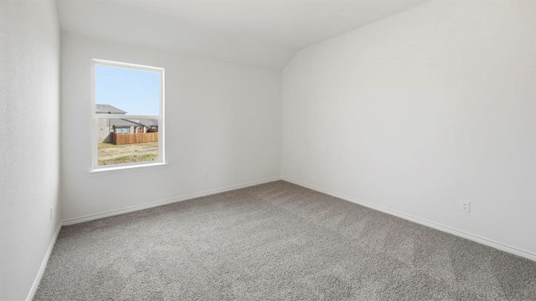 Carpeted empty room with vaulted ceiling and baseboards
