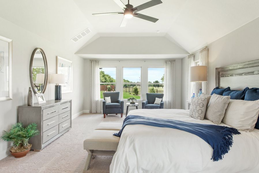 Master bedroom with vaulted ceiling, ceiling fan, sitting area by bay windows, and carpet flooring