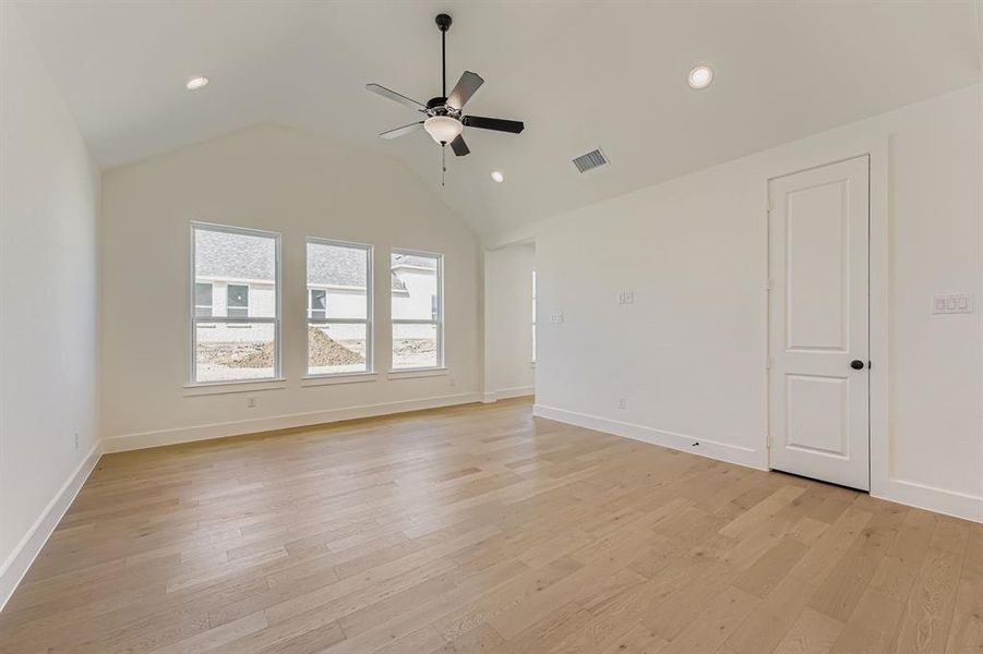 Empty room featuring lofted ceiling, light wood-type flooring, ceiling fan, and recessed lighting Empty room featuring lofted ceiling, light wood-type flooring, ceiling fan, and recessed lighting