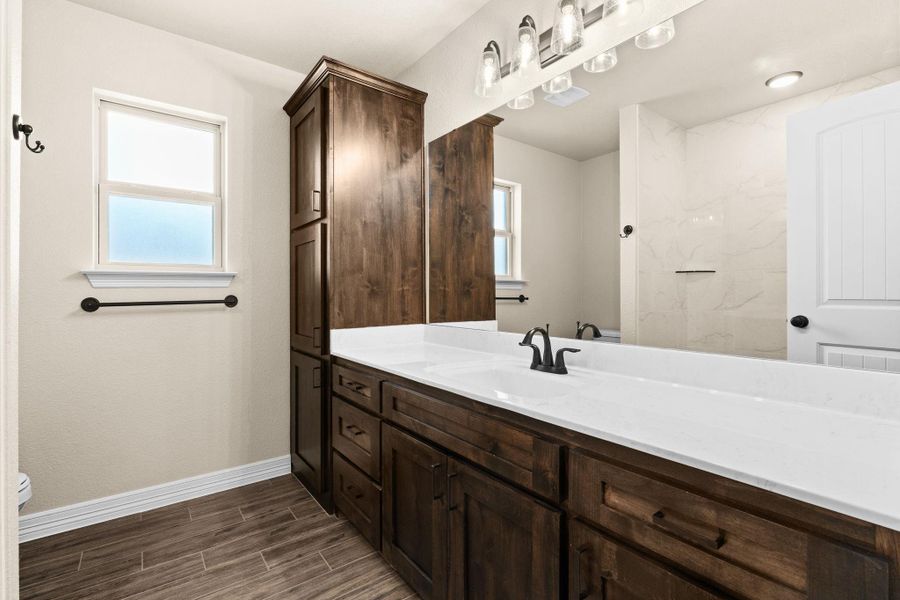 Full bathroom featuring vanity, dark brown cabinets, and wood like tiled floors Full bathroom featuring vanity, dark brown cabinets, and wood like tiled floors