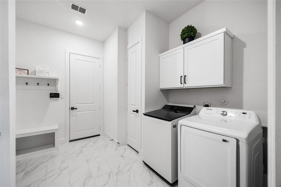 Well-appointed laundry room with built-in cabinetry, a convenient drop-off area, and dedicated folding space.