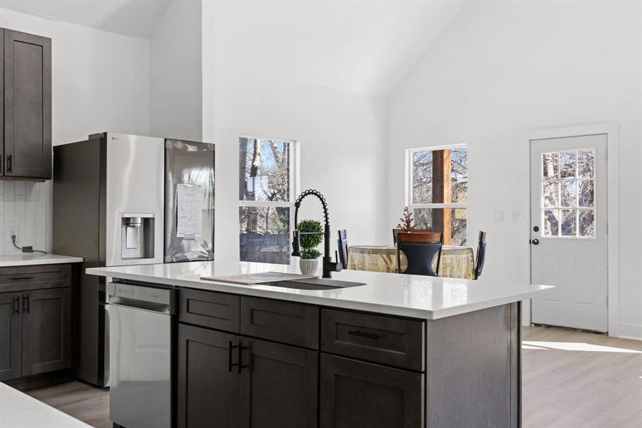 Kitchen featuring decorative backsplash, stainless steel fridge, sink, high vaulted ceiling, and a kitchen island