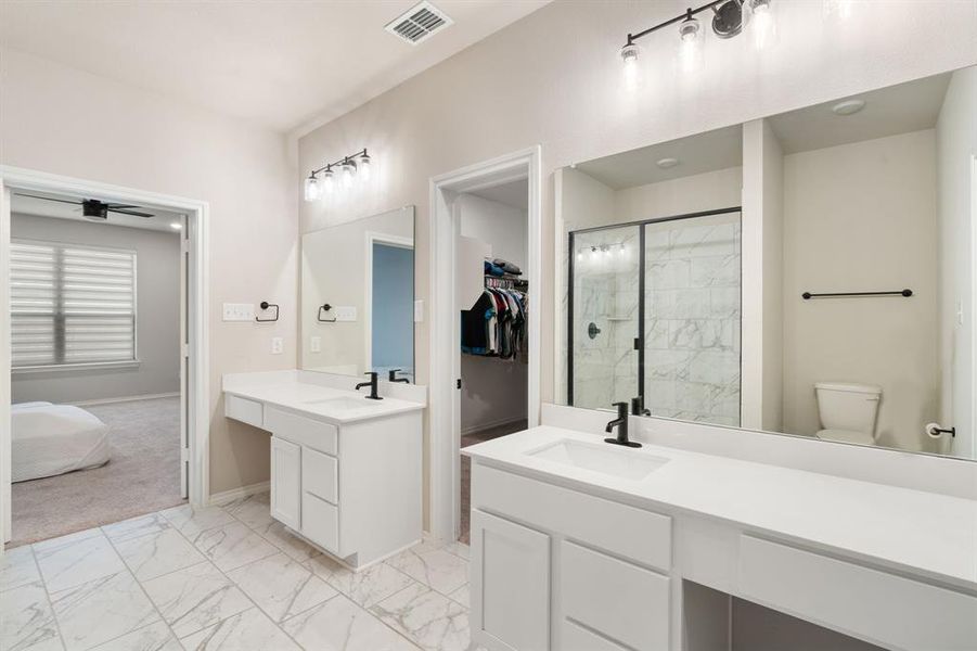 Full bathroom featuring light marble finish flooring, a marble finish shower, two vanities, and a spacious closet Full bathroom featuring light marble finish flooring, a marble finish shower, two vanities, and a spacious closet