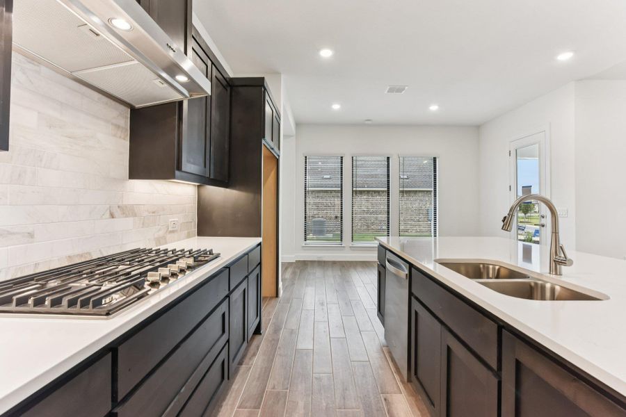Kitchen featuring wall chimney exhaust hood, appliances with stainless steel finishes, light stone counters, decorative backsplash, and recessed lighting Kitchen featuring wall chimney exhaust hood, appliances with stainless steel finishes, light stone counters, decorative backsplash, and recessed lighting