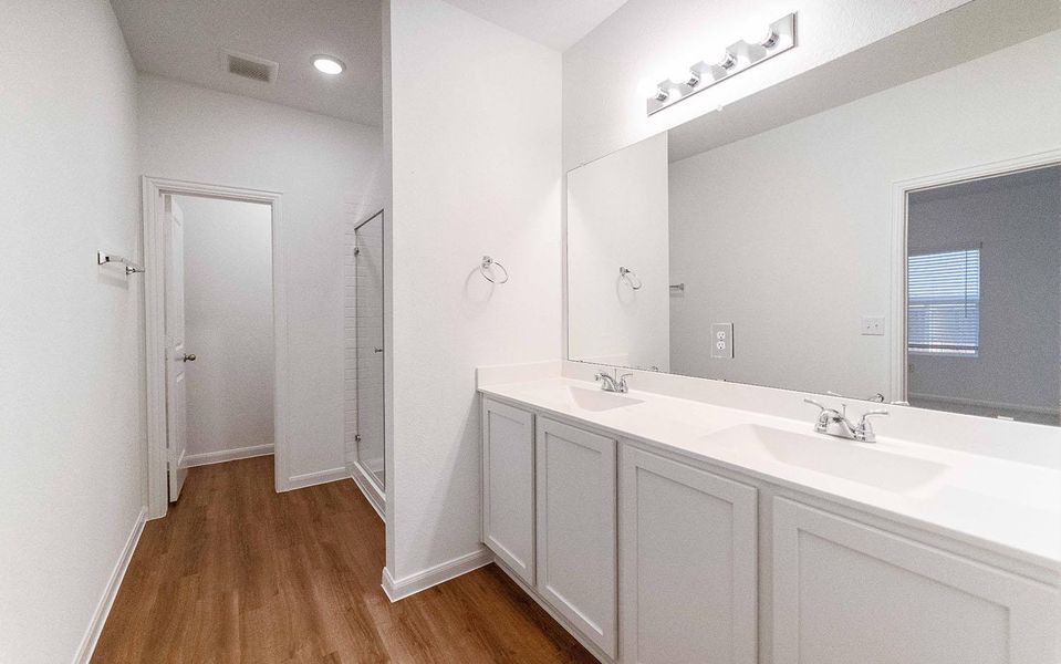 Full bathroom with double vanity, a stall shower, and light wood-style flooring Full bathroom with double vanity, a stall shower, and light wood-style flooring