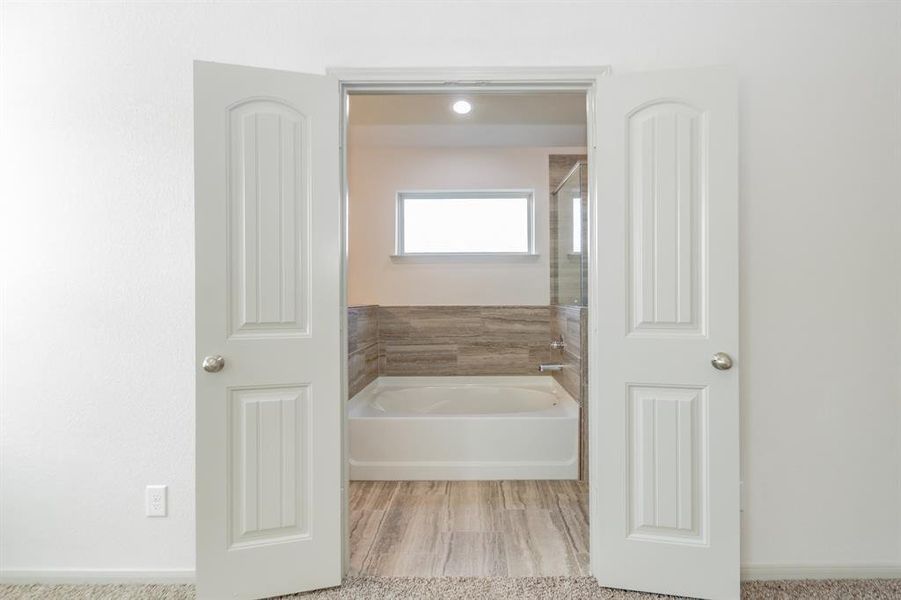 Step into luxury through these double doors that lead to the elegant primary bathroom. This space combines style and functionality with a soaking tub, tiled shower, and ample natural light. The seamless connection to the bedroom ensures your private oasis is always within reach.