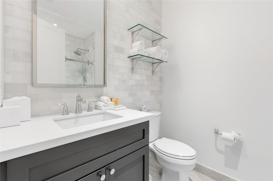 Full bath featuring backsplash, a shower stall, and vanity