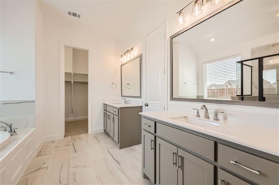 Bathroom with double vanity, tile flooring, and a relaxing tiled bath