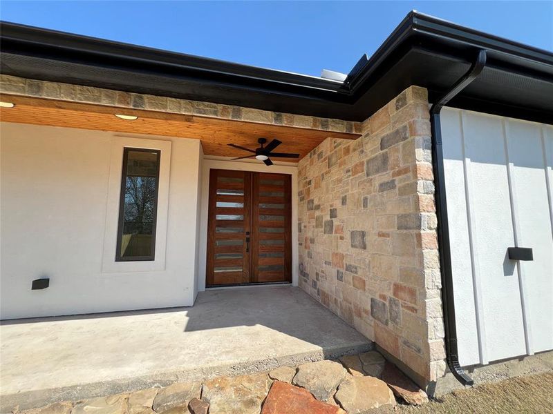 Backyard patio, stone siding, ceiling fan, and board and batten siding