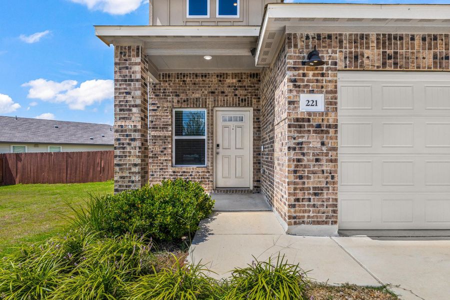 Doorway to property featuring brick siding, a garage, board and batten siding, and a porch Doorway to property featuring brick siding, a garage, board and batten siding, and a porch