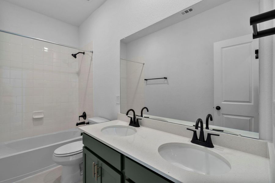 The secondary bath features tile flooring, green stained cabinetry and light countertops and a shower/tub combo. Perfect for accommodating any visiting family and friends. The secondary bath features tile flooring, green stained cabinetry and light countertops and a shower/tub combo. Perfect for accommodating any visiting family and friends.