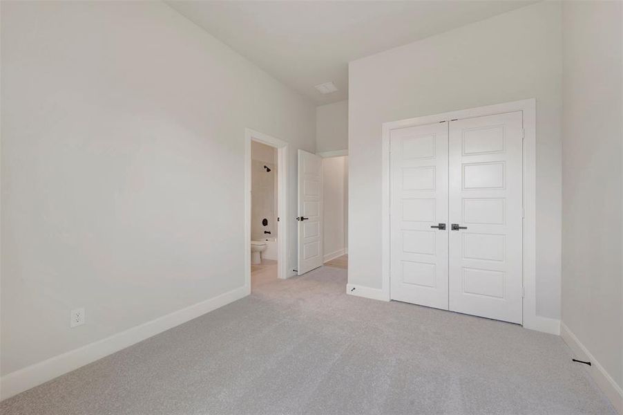Carpeted interior space featuring light gray walls, white trim, and a high ceiling