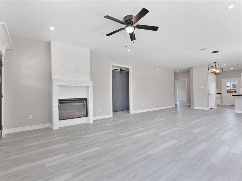 Unfurnished living room featuring baseboards, ceiling fan, a fireplace, recessed lighting, and light wood-style floors Unfurnished living room featuring baseboards, ceiling fan, a fireplace, recessed lighting, and light wood-style floors
