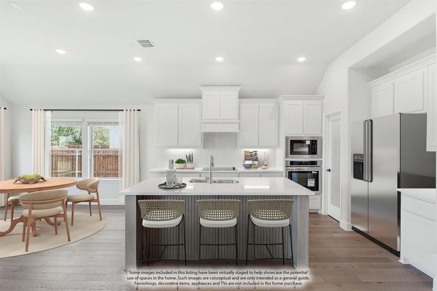 Kitchen with white cabinets, center island with seating, stainless steel appliances, and adjacent dining area with hardwood floors.