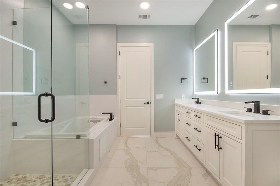 Full bath featuring double vanity, a bath, light marble finish floors, and a shower stall