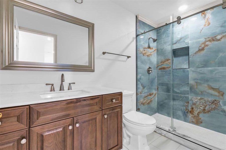 Bathroom with tile patterned floors, vanity, an enclosed shower, and toilet