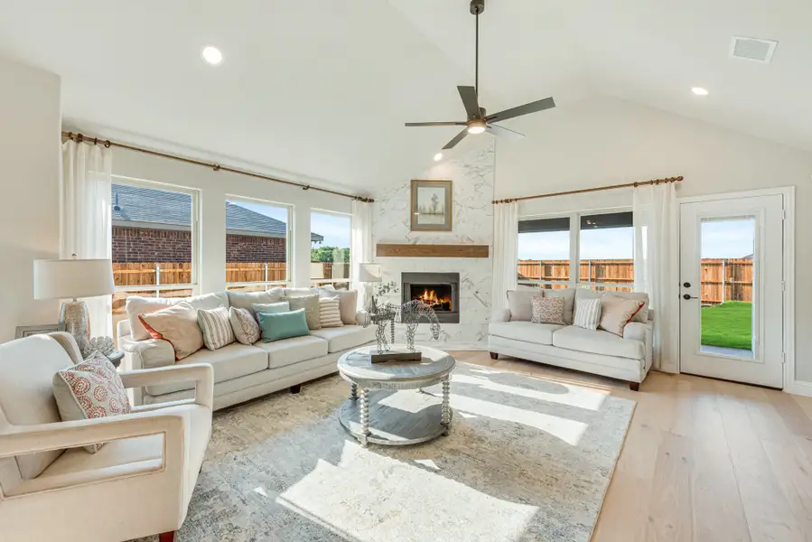 Living room with vaulted ceiling, marble fireplace, hardwood floors, and ceiling fan