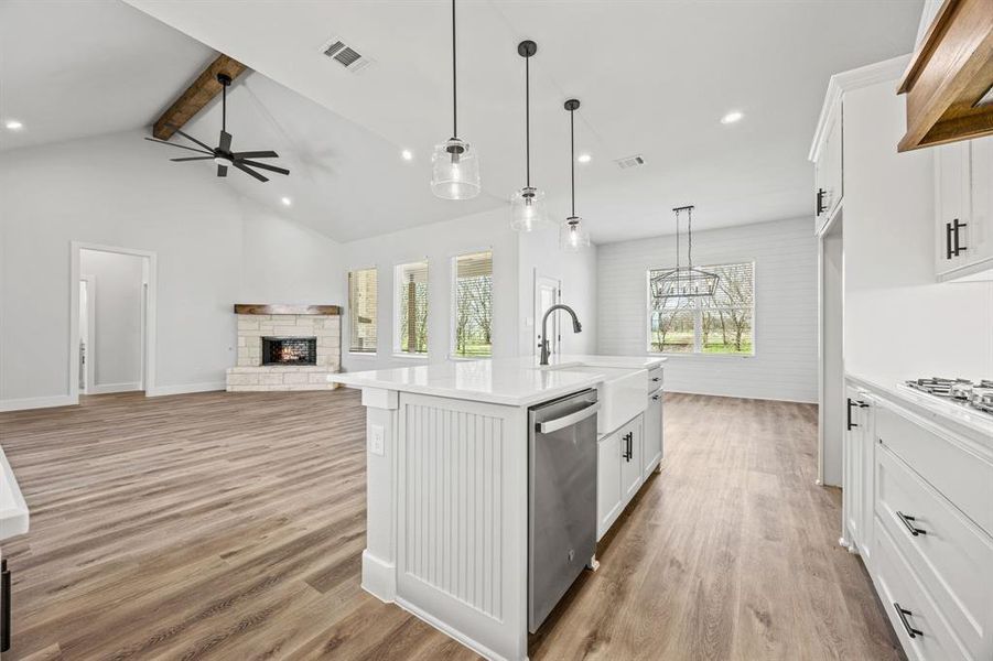 Kitchen featuring light countertops, a fireplace, beam ceiling, light wood-type flooring, and white cabinets Kitchen featuring light countertops, a fireplace, beam ceiling, light wood-type flooring, and white cabinets