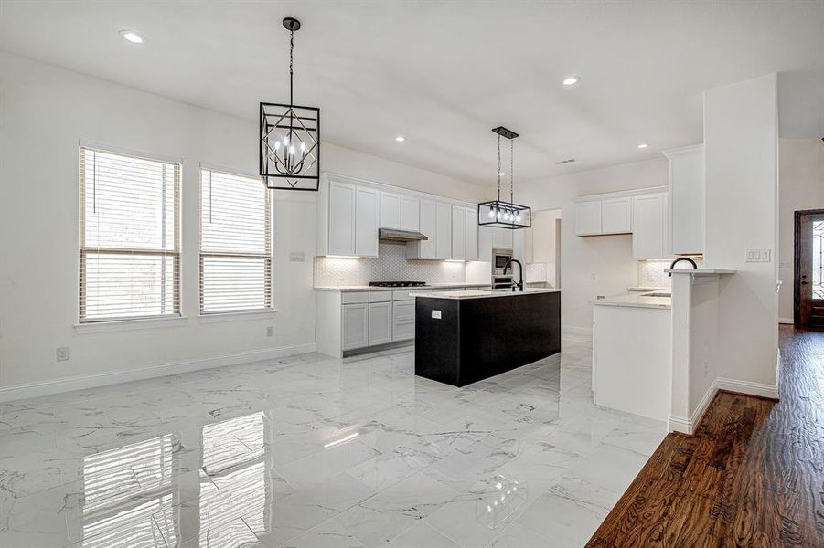 Kitchen featuring decorative light fixtures, gas stovetop, white cabinetry, and tasteful backsplash