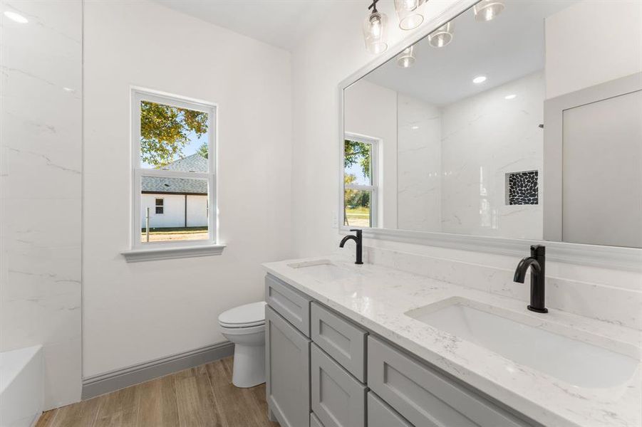 Full bath featuring double vanity, light wood-style flooring, and recessed lighting