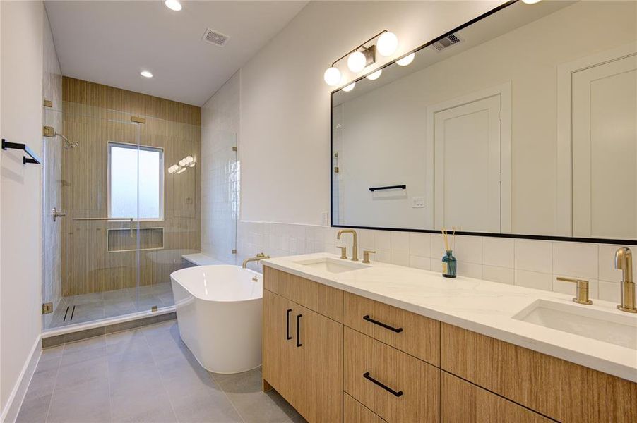 Stunning primary bathroom with clean, contemporary tilework, large shower with sleek linear drain, and soaking tub.