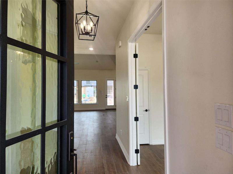 Entryway featuring a black metal and textured glass door, vaulted ceiling, contemporary geometric pendant light, recessed lighting, and wood-finish flooring