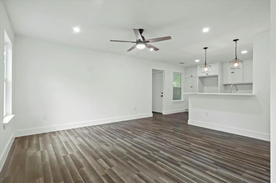 Unfurnished living room with ceiling fan, dark hardwood / wood-style floors, and sink