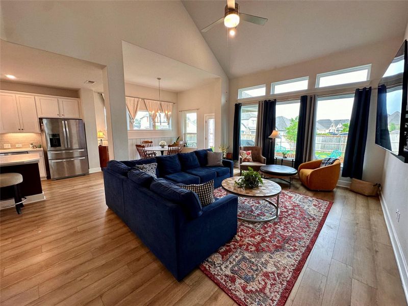 Living area with vaulted ceiling, wood-finish flooring, and expansive windows throughout giving an abundance of natural light.