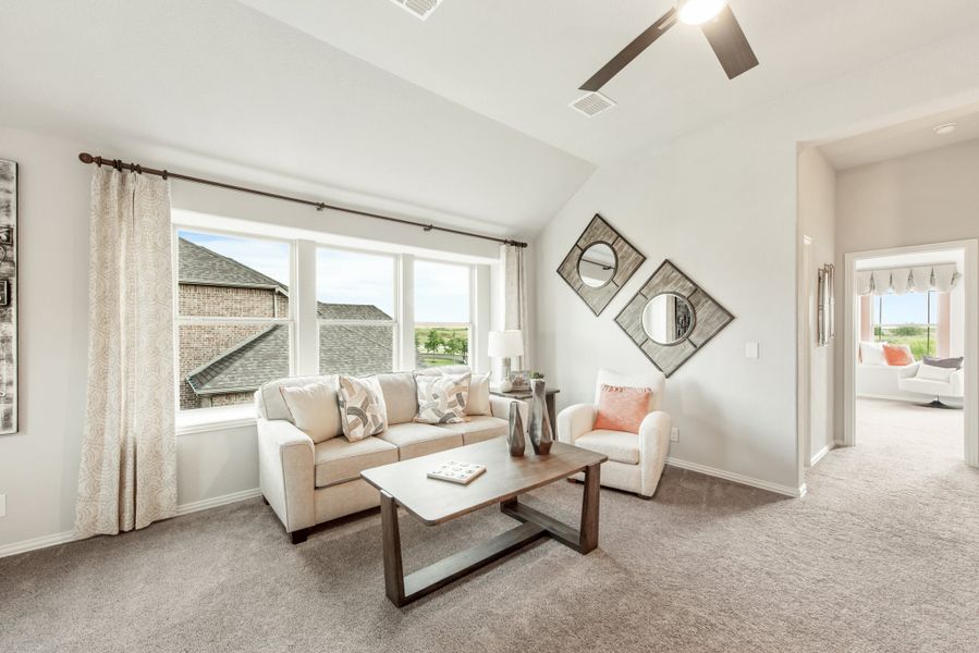 Living room with vaulted ceiling, ceiling fan, large windows, beige sofa, and carpeted floors